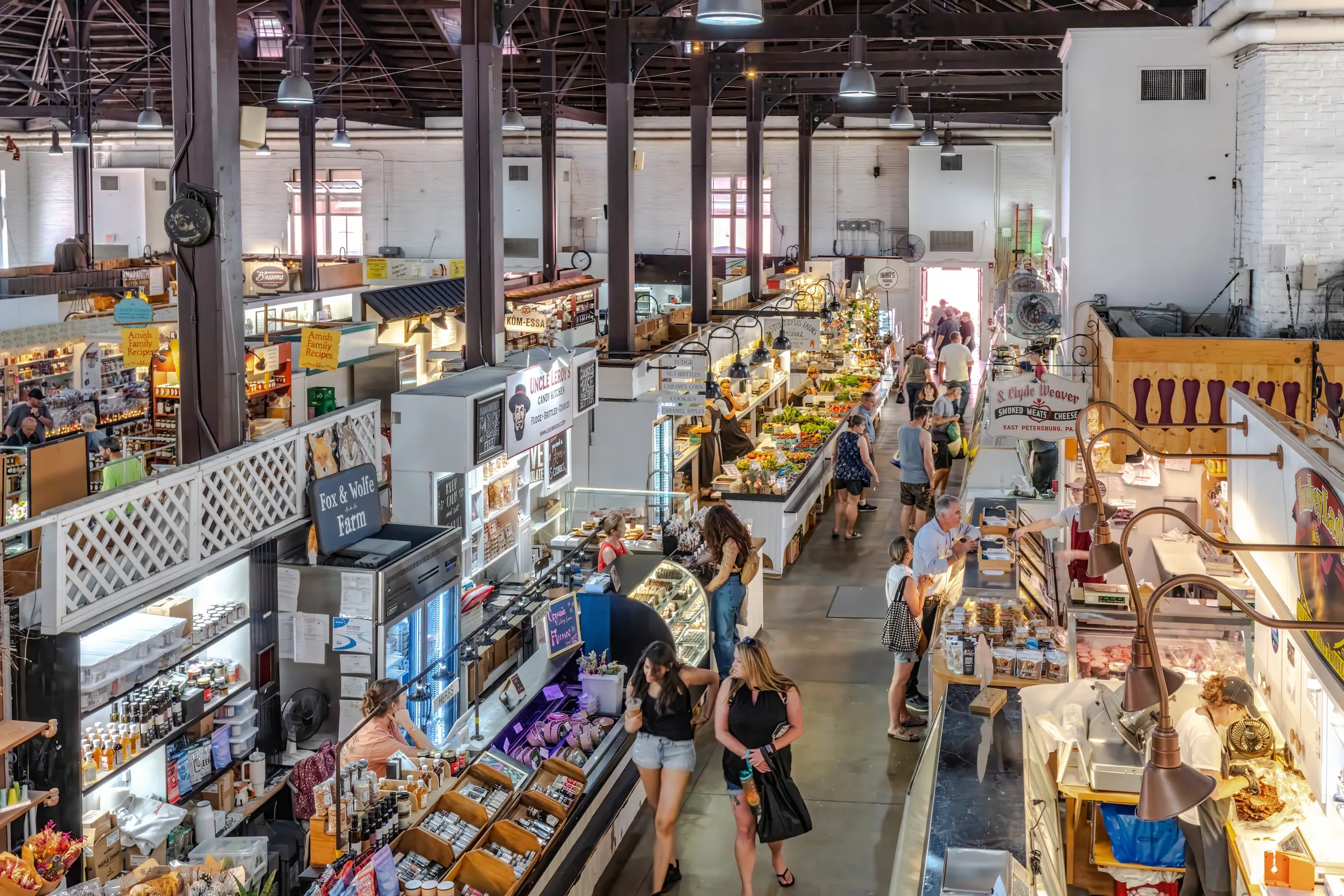 Shoppers walking between food and produce stalls inside Lancaster Central Market