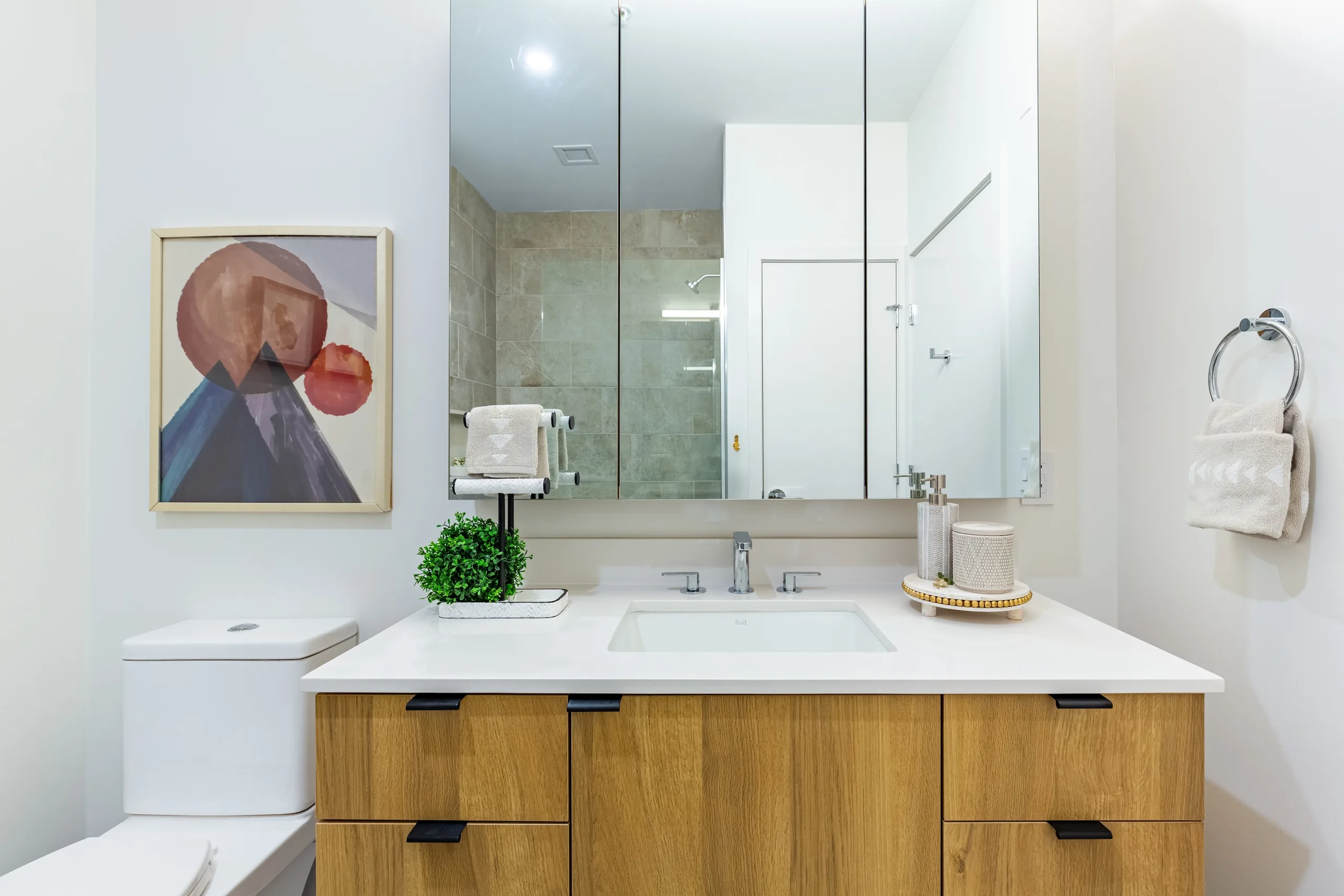 Quartz vanity, drawer storage and three-door medicine cabinet in a model bathroom