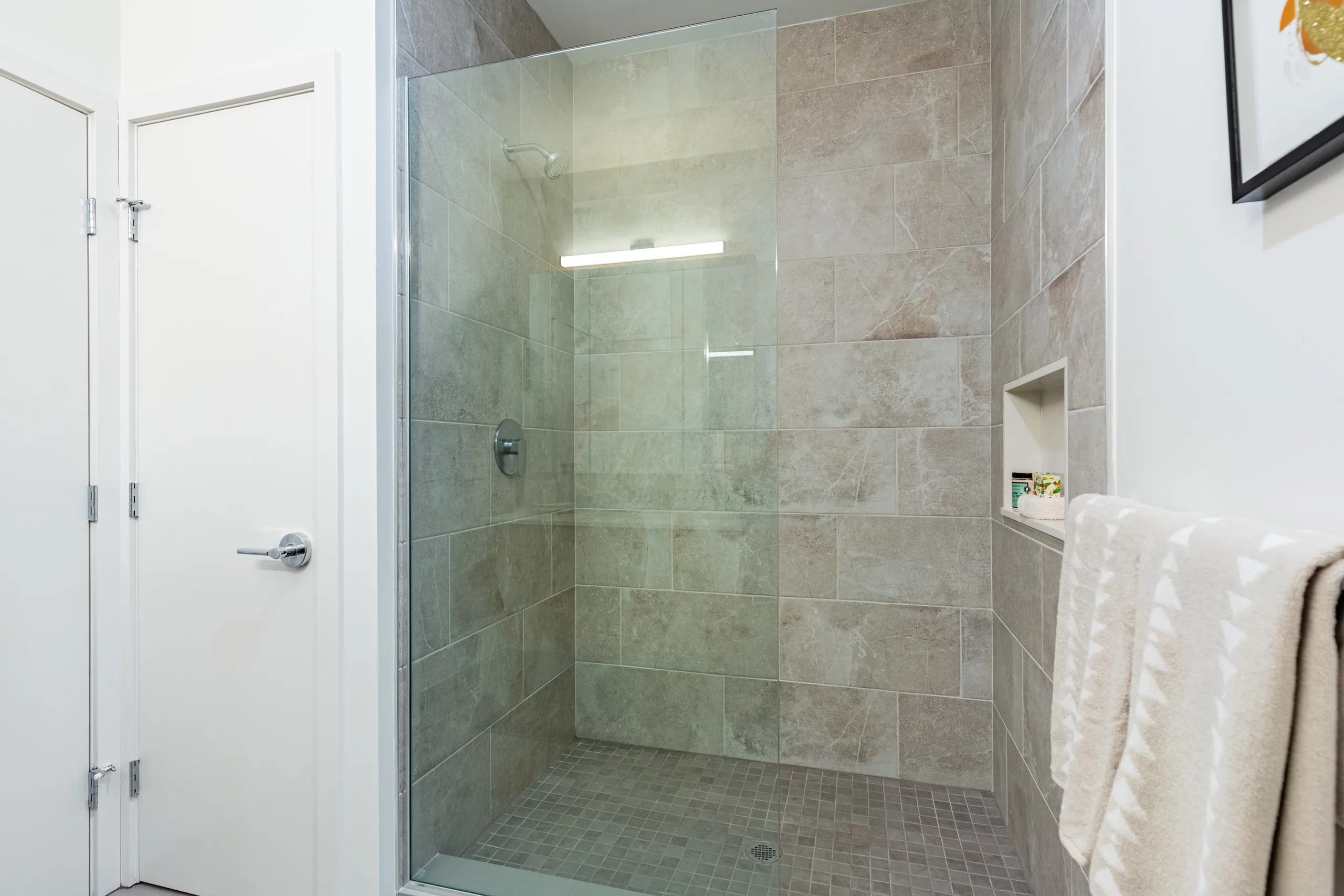 Glass-enclosed shower and tiled bathroom at The Alistair
