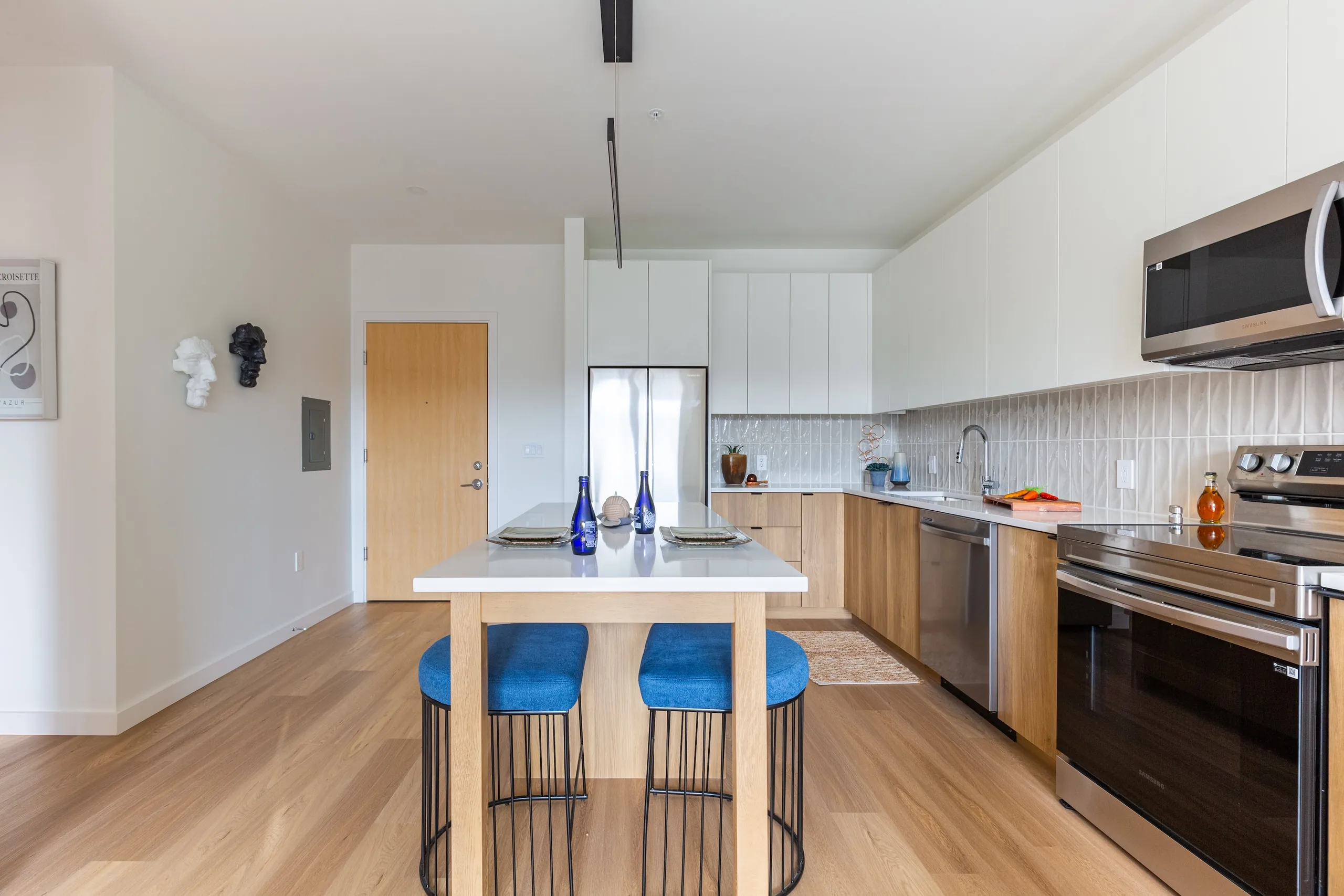 Apartment kitchen with an island, blue stools and stainless steel appliances