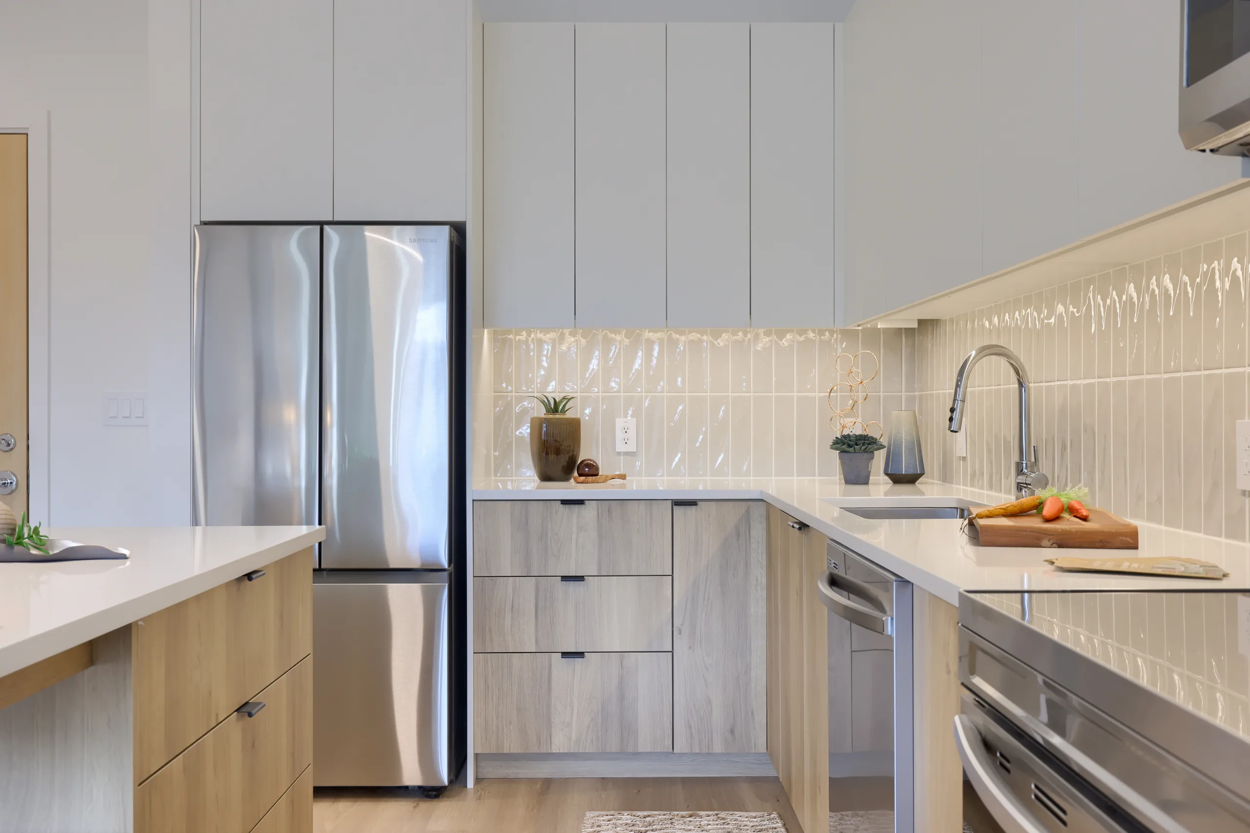 Apartment kitchen with pale cabinetry, refrigerator and a tiled backsplash