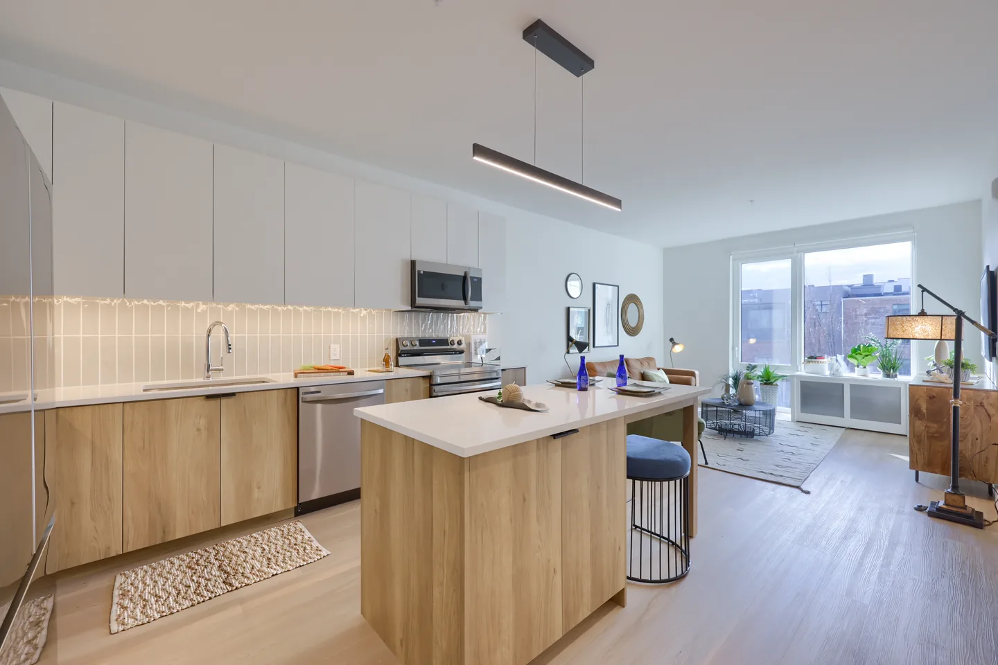 Kitchen with a large island, light wood cabinetry and an adjoining living area by a window
